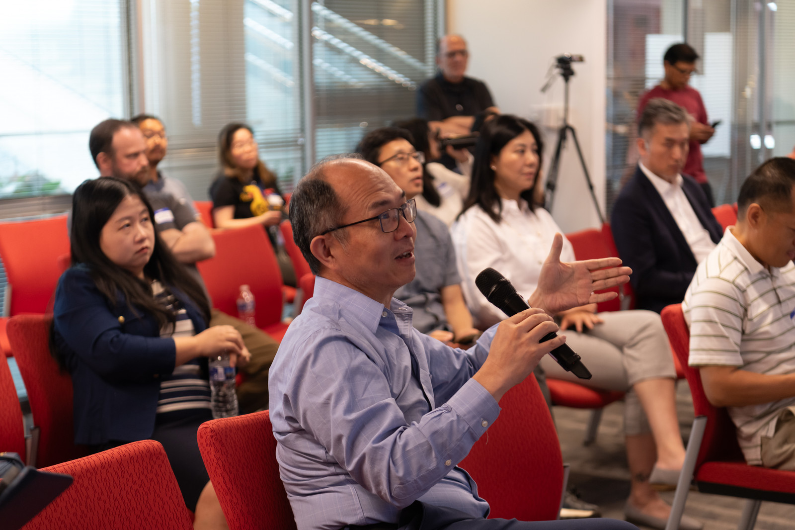 An attendee stands to ask a question with a microphone during a session.