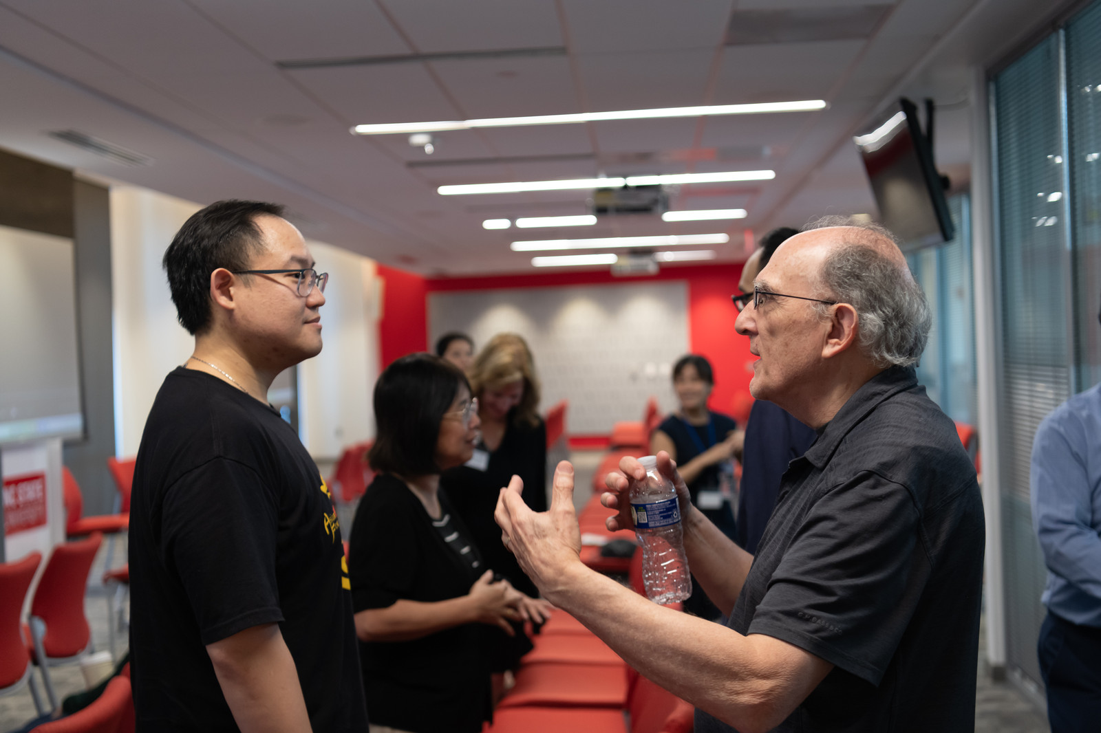 Two attendees talk one-on-one during a networking break in the conference room.