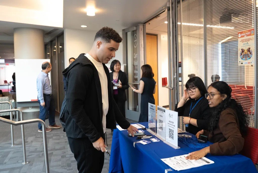 An attendee checks in at the welcome table, staffed by student volunteers, at the start of the conference.
