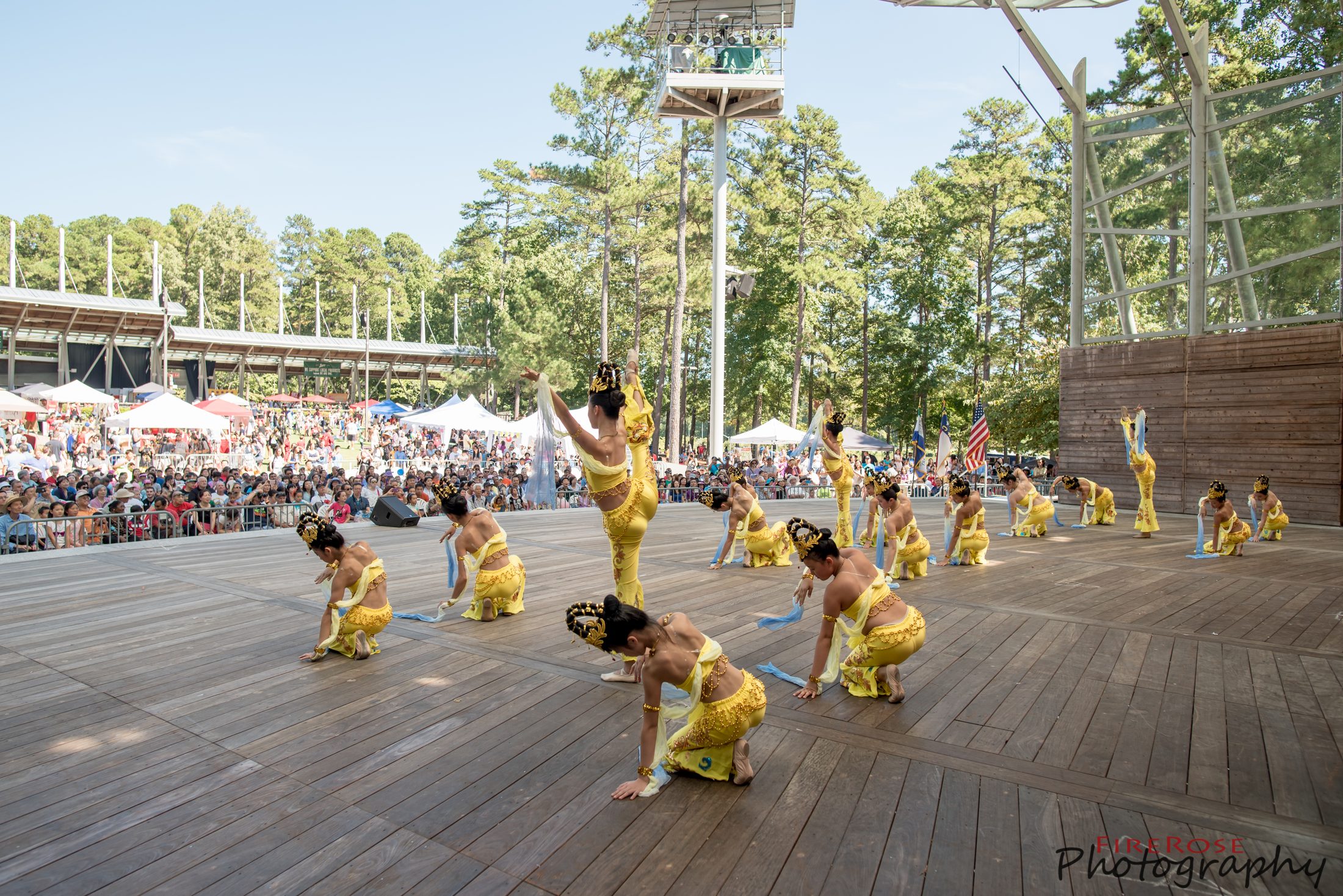 Dancers in yellow costumes performing before a large seated crowd at the amphitheatre